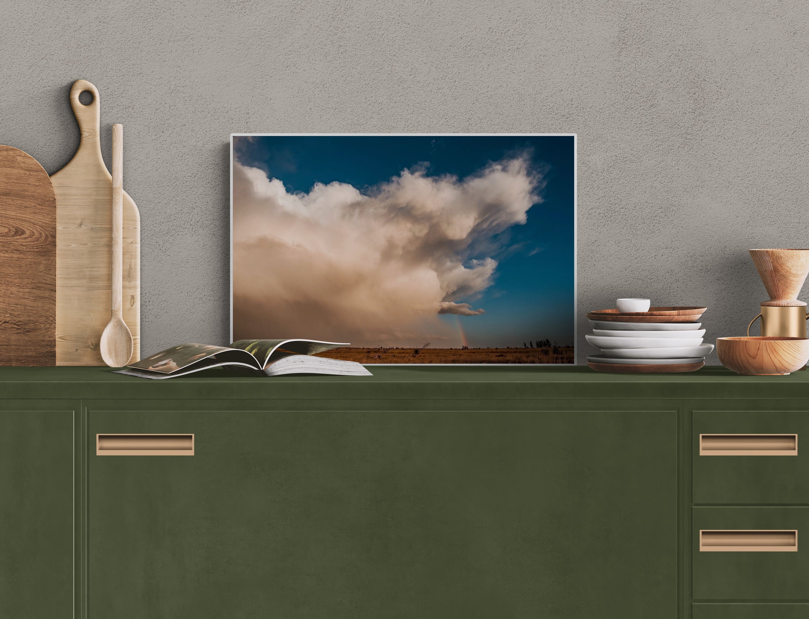 Culinary-themed setup with a contemporary art displaying a cloud scene, books, and kitchen items on a green cabinet.